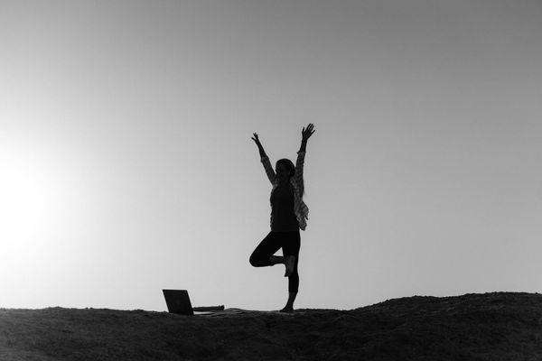 Silhouette of a person in a meditation pose at sunrise.